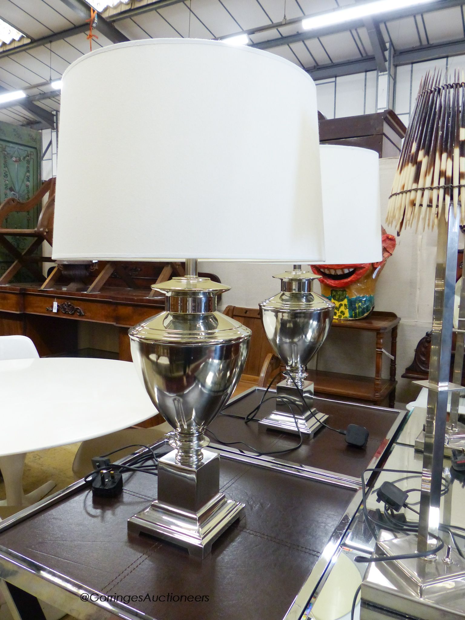 A pair of chrome urn form table lamps with cream shades by Andrew Martin
